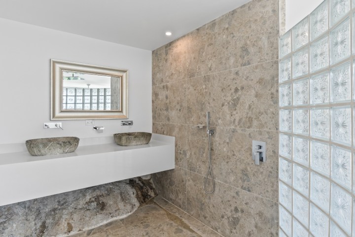 Modern bathroom with stone sinks and glass brick shower wall.