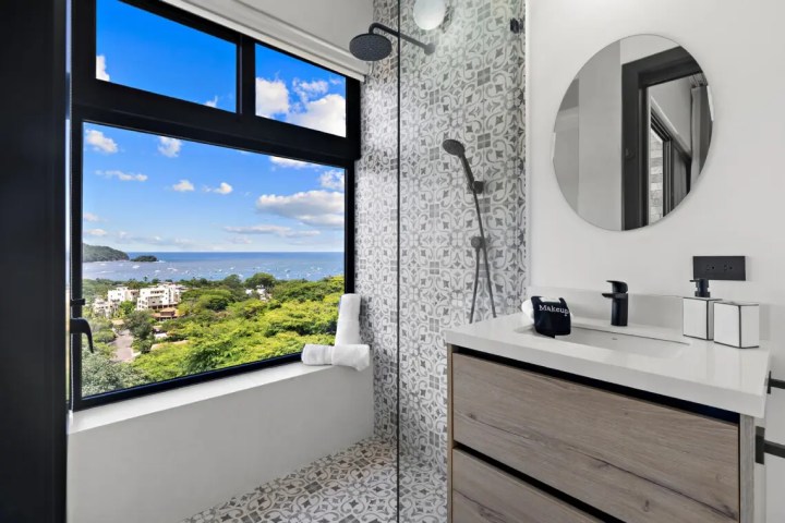 Modern bathroom with large window showing ocean view.