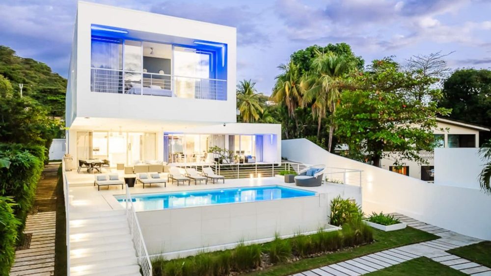 Modern two-story house with large windows and a pool in the backyard.