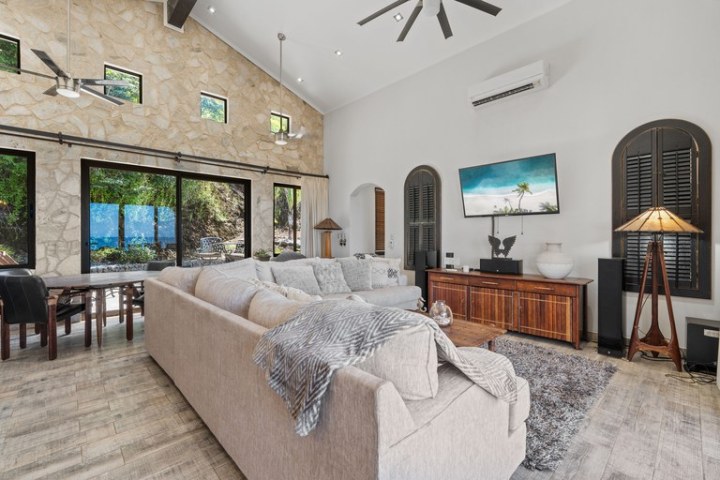 Spacious living room with stone wall, large windows, and cozy furniture.