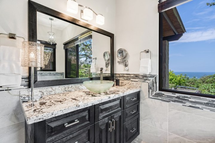 Modern bathroom with a granite countertop and ocean view window.