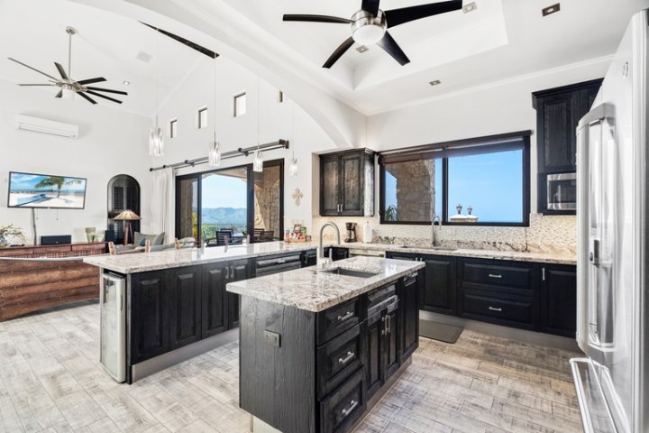 Modern kitchen with dark wood cabinets, granite countertops, and ceiling fans.