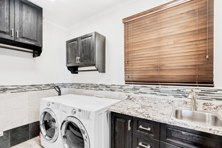 Laundry room with washer, dryer, cabinets, and sink.