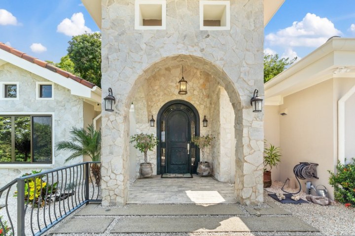 Stone archway entrance with black door and hanging lantern.