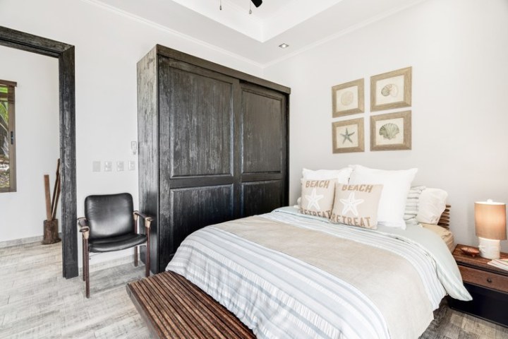 Cozy bedroom with a bed, wooden wardrobe, chair, and beach-themed decor.