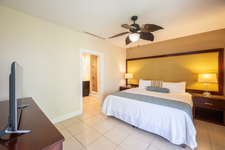 Spacious hotel room with king bed, TV, lamps, and ceiling fan.