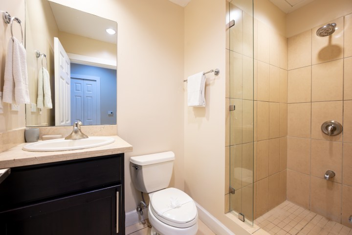 Modern bathroom with shower, toilet, and sink with mirror.