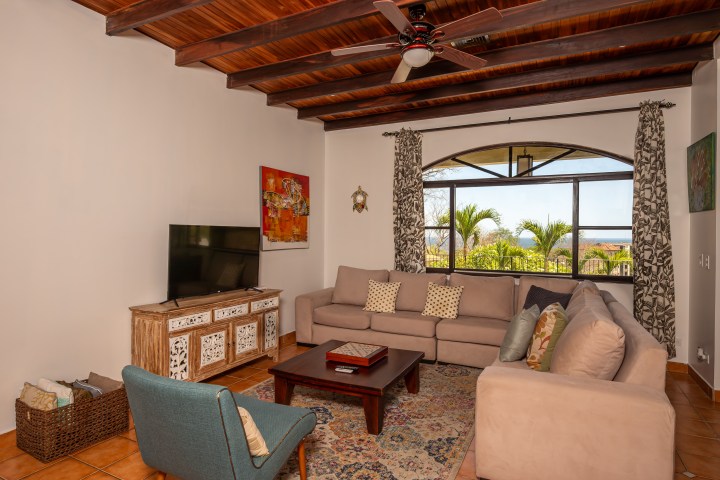 Cozy living room with two sofas, a TV, and a large window with garden view.