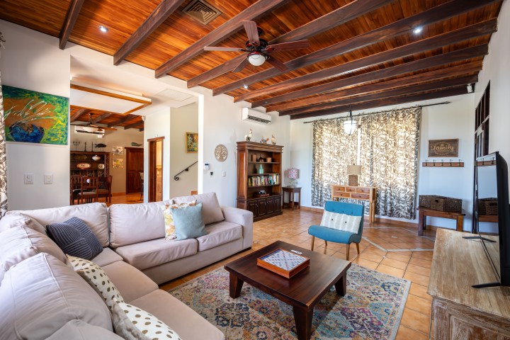 Spacious living room with wooden beams, cozy sofas, rug, and a TV.