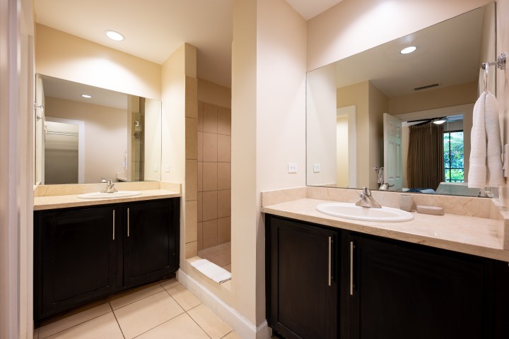 Modern bathroom with two mirrors, dual sinks, and a walk-in shower.