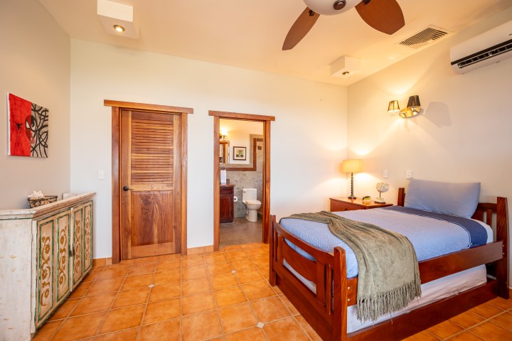 Cozy bedroom with single bed, wooden doors, and tiled floor.