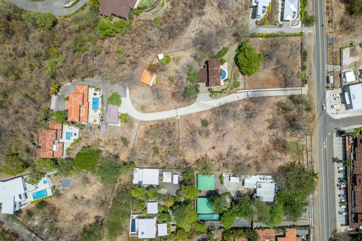 Aerial view of houses, roads, and trees in a dry landscape.