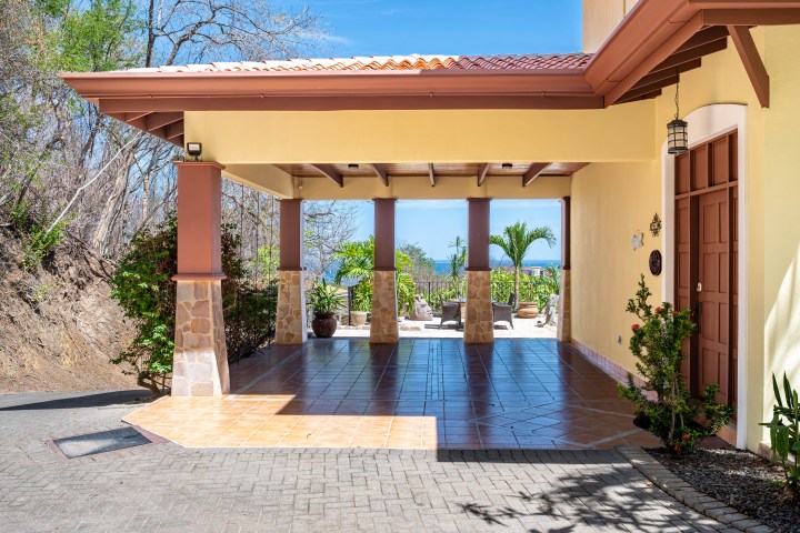 Open-air terrace with tiled floor, sea view, and palm trees in the background.
