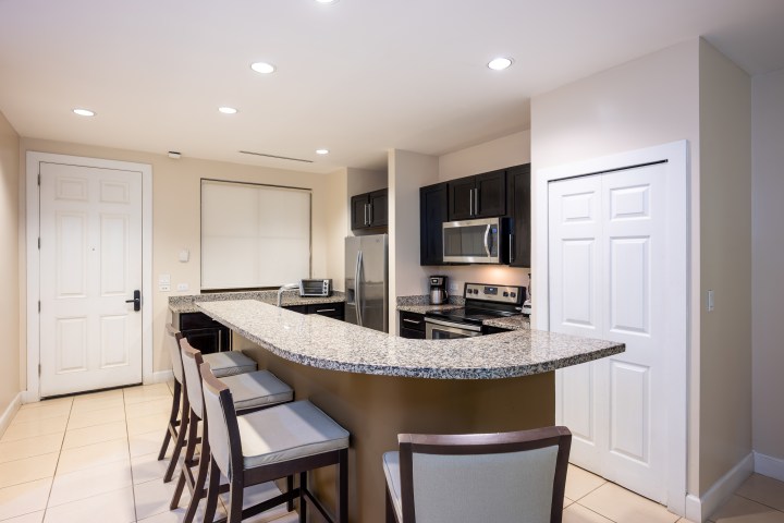 Modern kitchen with island, barstools, and stainless steel appliances.