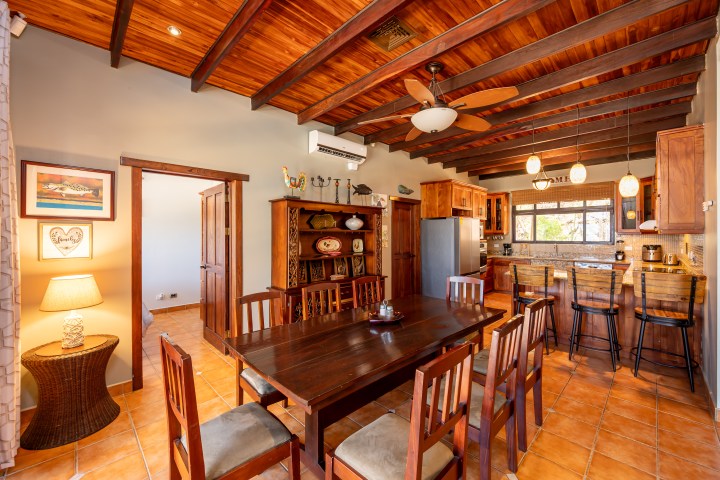 Warm dining room with wooden ceiling, kitchen island, and pendant lights.