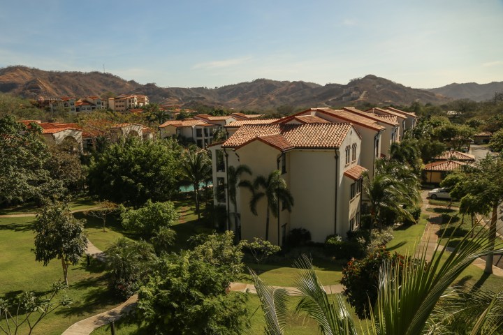 Houses with red roofs surrounded by trees and mountains.