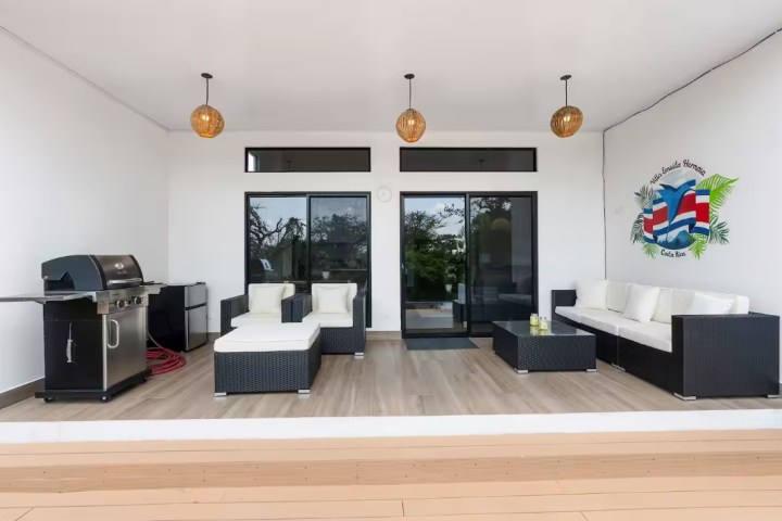Outdoor patio with sofas, grill, and hanging lights.