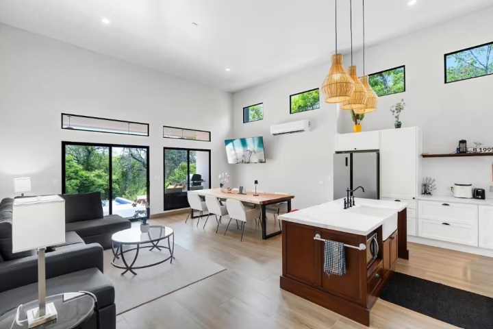 Modern open-concept living room and kitchen with large windows and stylish furniture.