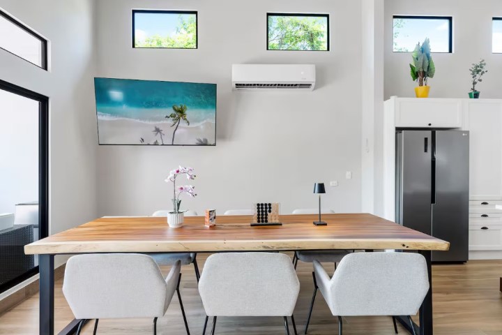 Modern dining room with wood table, chairs, and wall-mounted TV.