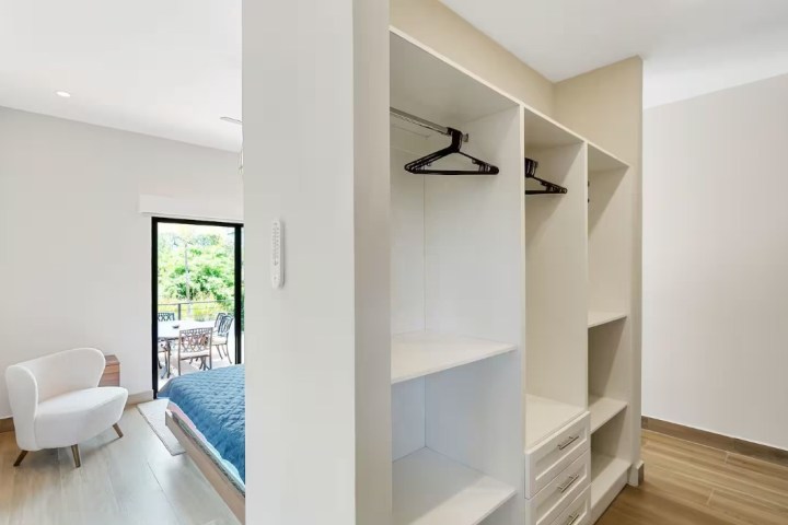 Modern bedroom with closet, minimalist decor, and balcony view.