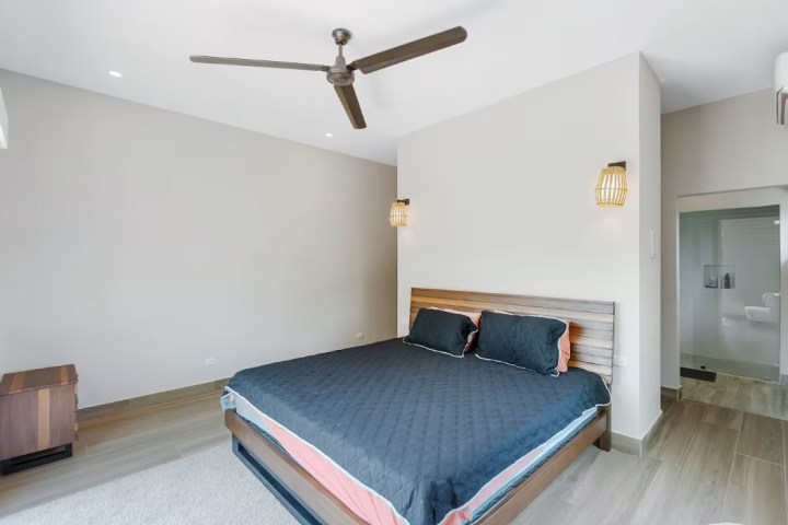 Modern bedroom with a double bed, ceiling fan, and bathroom entrance.