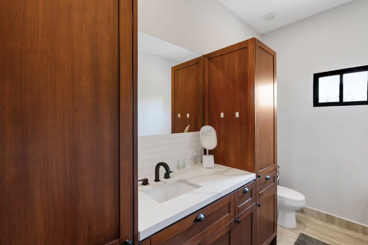 Modern bathroom with wooden cabinets and a white sink.