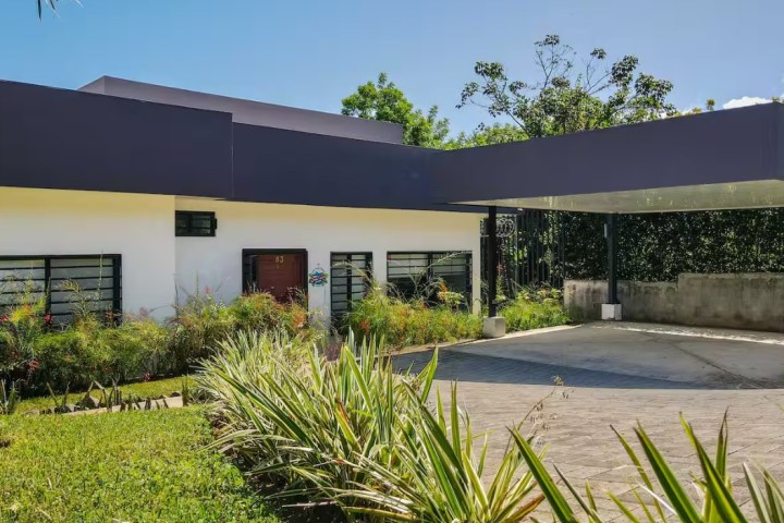 Modern house with flat roof, large windows, and a spacious driveway.