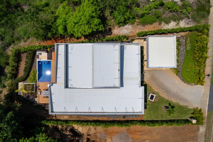 Aerial view of a house with a pool, surrounded by greenery.