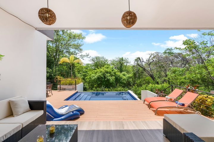 Modern patio with pool, lounge chairs, and greenery.
