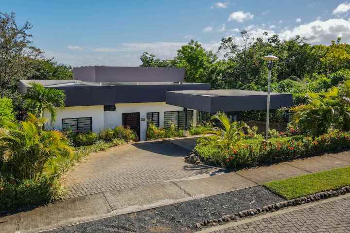 Modern house with flat roof, surrounded by tropical plants.