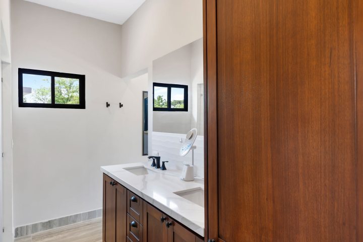 Modern bathroom with dual sinks, mirror, and wooden cabinetry.
