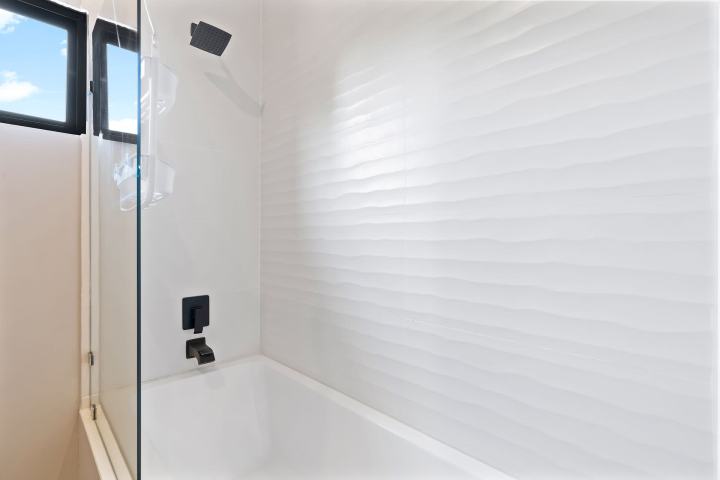 White bathroom with tub, glass partition, and modern fixtures.