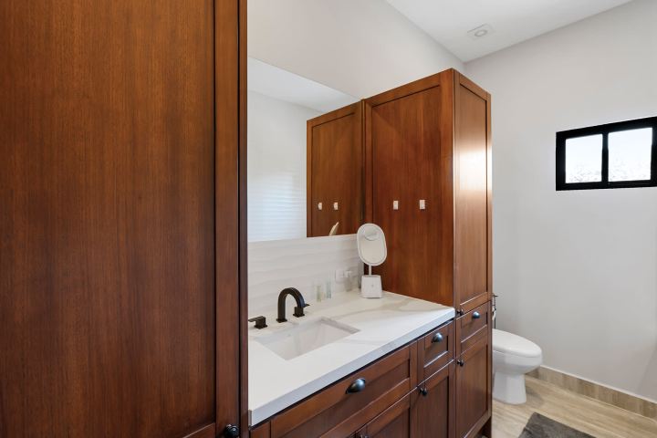 Bathroom with wooden cabinets, white countertop, and a small window.