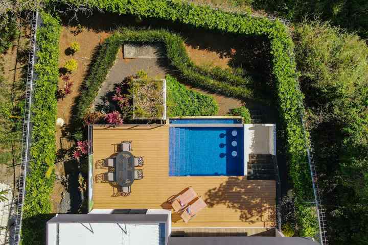 Aerial view of a fenced backyard with a pool, deck, and outdoor dining area.