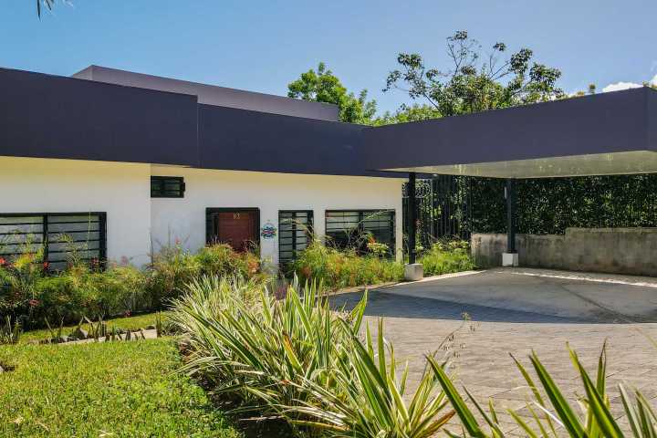 Modern house with flat roof, carport, and landscaped garden.
