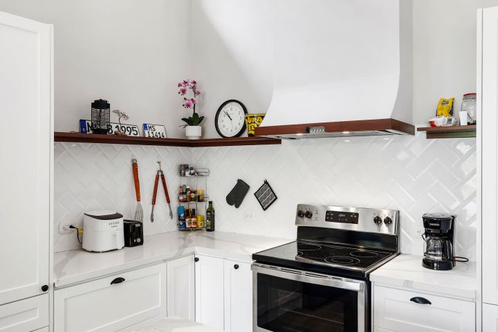Modern kitchen with white cabinets, stove, toaster, and coffee maker.