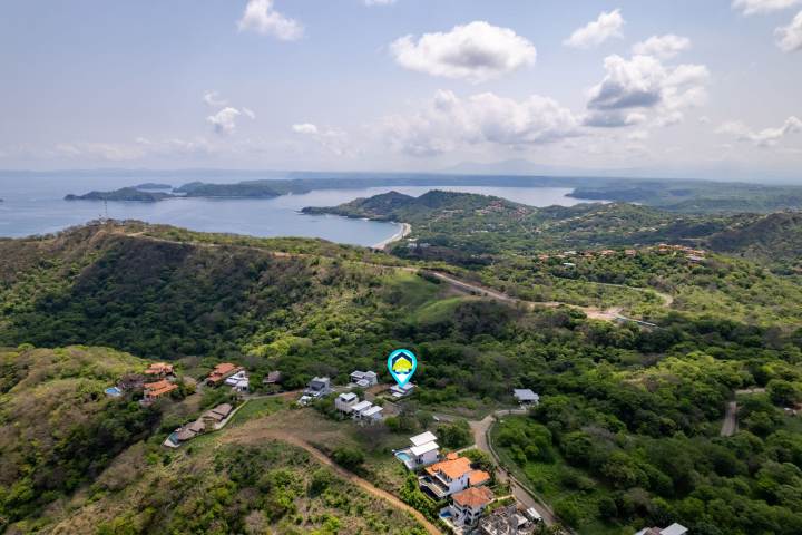 Aerial view of coastal landscape with scattered houses and lush greenery.
