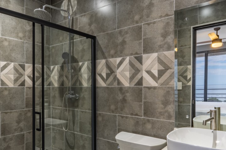 Modern bathroom with shower, sink, and toilet, featuring geometric tile design.