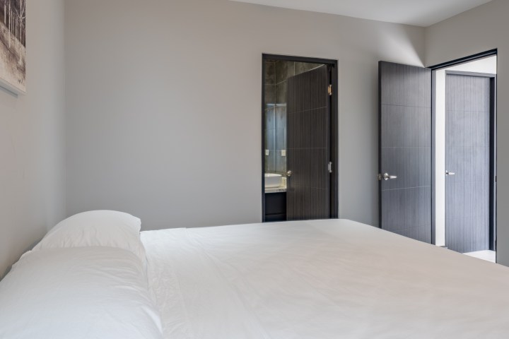 Minimalist bedroom with double doors and a bed.
