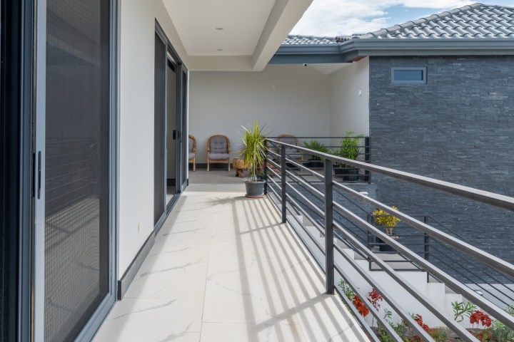 Modern balcony with railings, potted plants, and sliding doors.