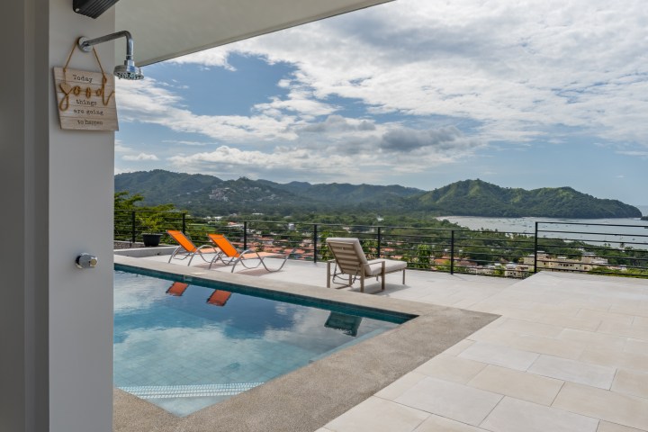 Poolside patio with lounge chairs overlooking a scenic coastal view.