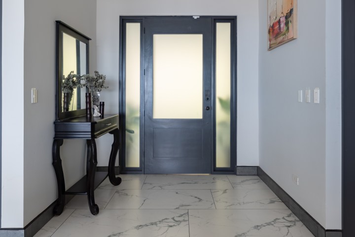 Modern hallway with a mirror, table, and a gray door.