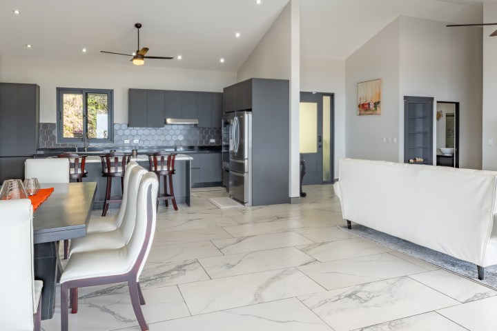 Modern open-plan kitchen and living room with gray cabinets and white seating.