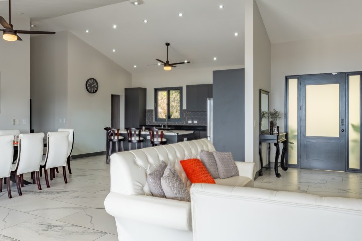 Modern open-plan living area with white sofas and dining table.