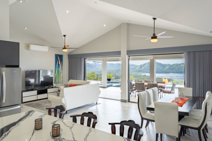 Open living space with kitchen, dining, and seating area, overlooking mountains and patio through large windows.