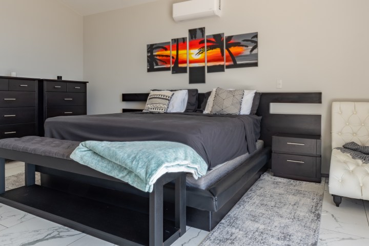 Modern bedroom with black furniture and abstract artwork above the bed.
