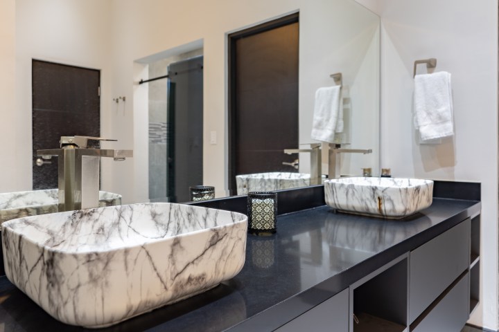 Modern bathroom with marble sink, large mirror, and black counter.