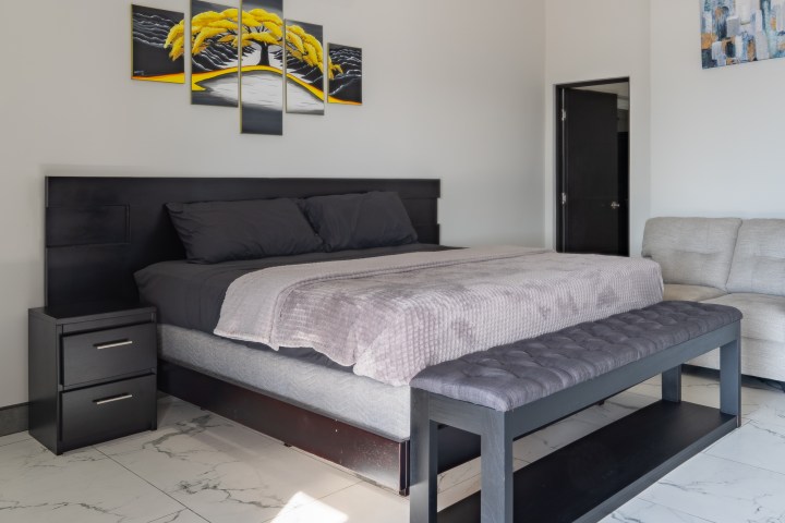 Modern bedroom with a black bed, bench, and abstract wall art.