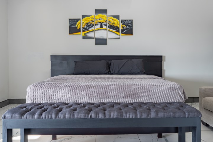 Modern bedroom with a dark bed, decorative artwork above.