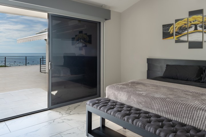 Modern bedroom with ocean view from sliding doors.